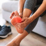 Persona palpando su pie por dolor de fascitis plantar